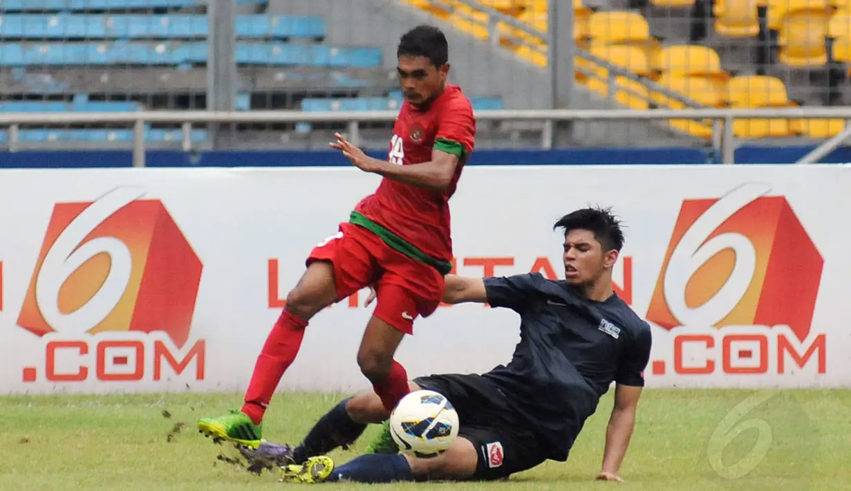 Pemain depan timnas U-19 Indonesia, Rifal Lastoni (kiri) berusaha menghindar terjangan salah satu pemain timnas U-19 Singapura saat berlaga di Stadion GBK Jakarta, (8/12/2014). Indonesia unggul 1-0 atas Singapura. (Liputan6.com/Helmi Fithriansyah)