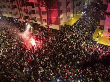 Ribuan warga Maroko berkumpul merayakan kemenangan Maroko atas Spanyol dalam pertandingan Piala Dunia 2022, di Rabat, Maroko, Selasa (6/12/2022). Meski Spanyol menguasai bola lebih banyak namun tidak mendapatkan peluang untuk membobol gawang Maroko. (AP Photo/Mosa’ab Elshamy)