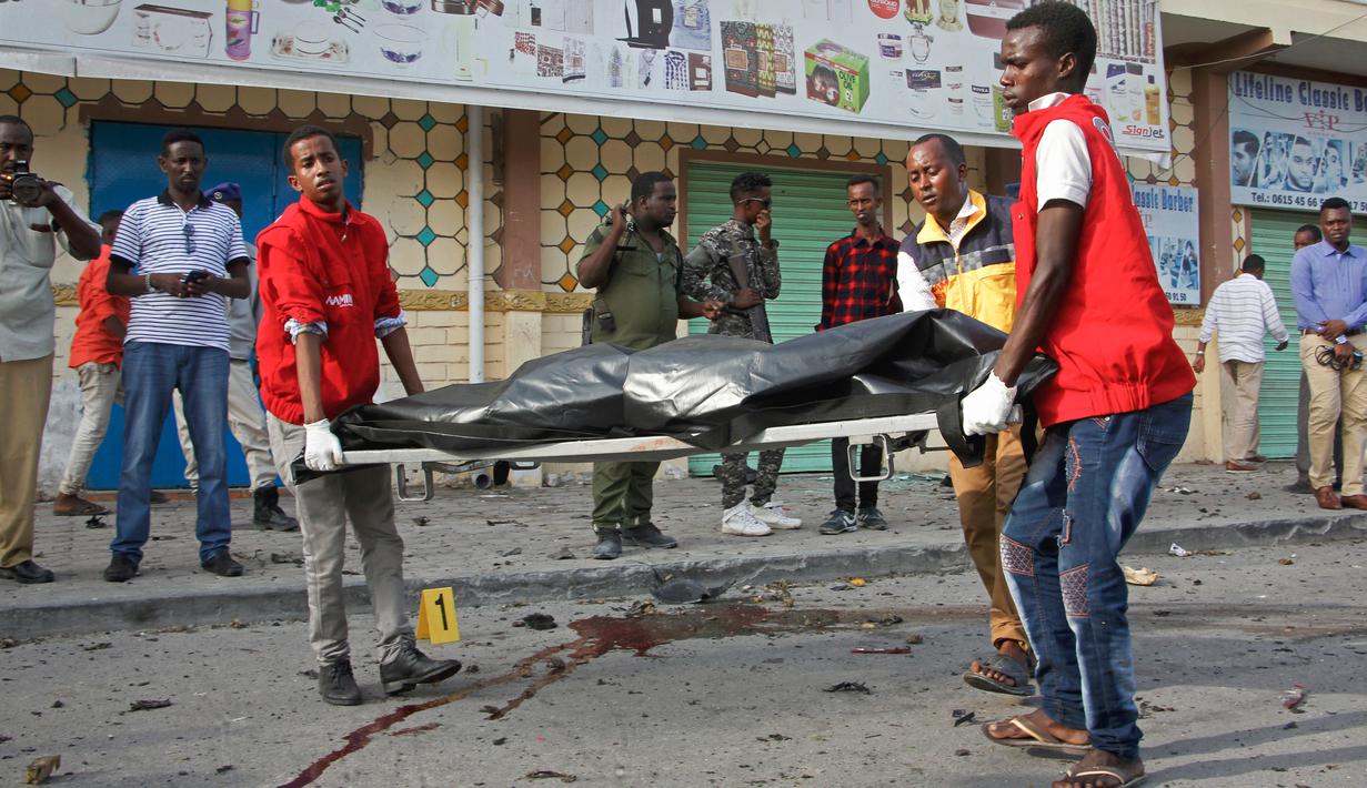 Petugas medis mengevakuasi jasad warga sipil dari lokasi ledakan bom mobil di dekat pos pemeriksaan parlemen dan Kementerian Dalam Negeri di Ibu Kota Somalia, Mogadishu, Minggu (25/3). Serangan menewaskan empat orang. (AP/Farah Abdi Warsameh)