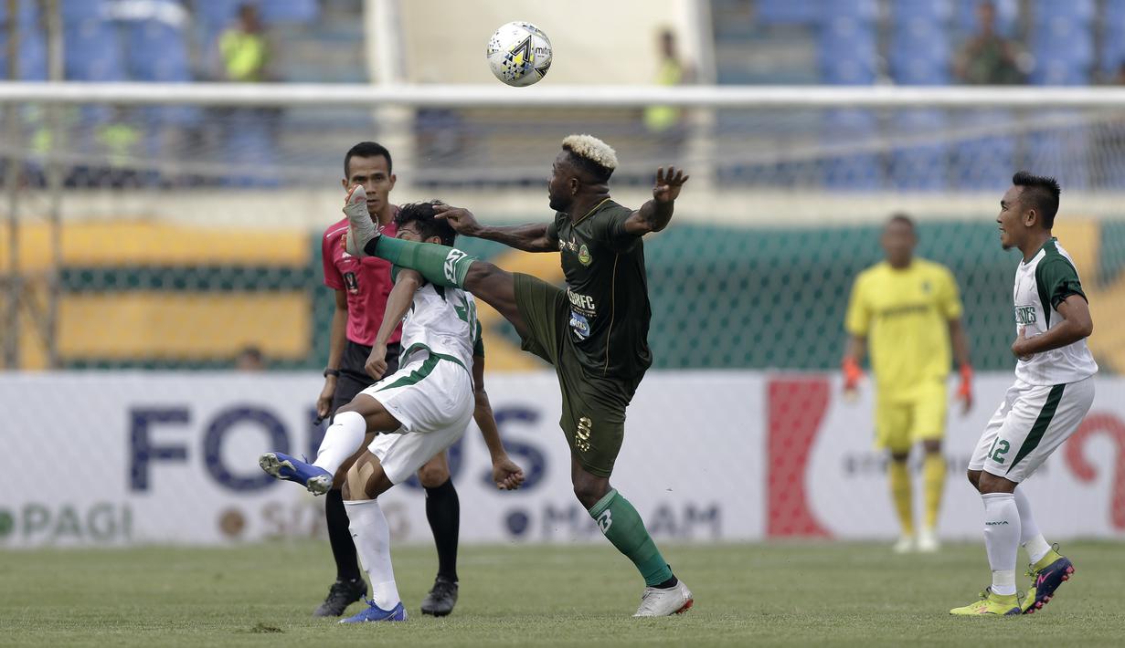Gelandang Tira Persikabo, Essengeu Eloumou, berebut bola dengan pemain Persebaya pada laga Piala Presiden 2019 di Stadion Si Jalakl Harupat, Soreang, Bandung, Selasa (12/3). Persebaya bermain imbang 0-0  atas Tira Persikabo. (Bola.com/Yoppy Renato)
