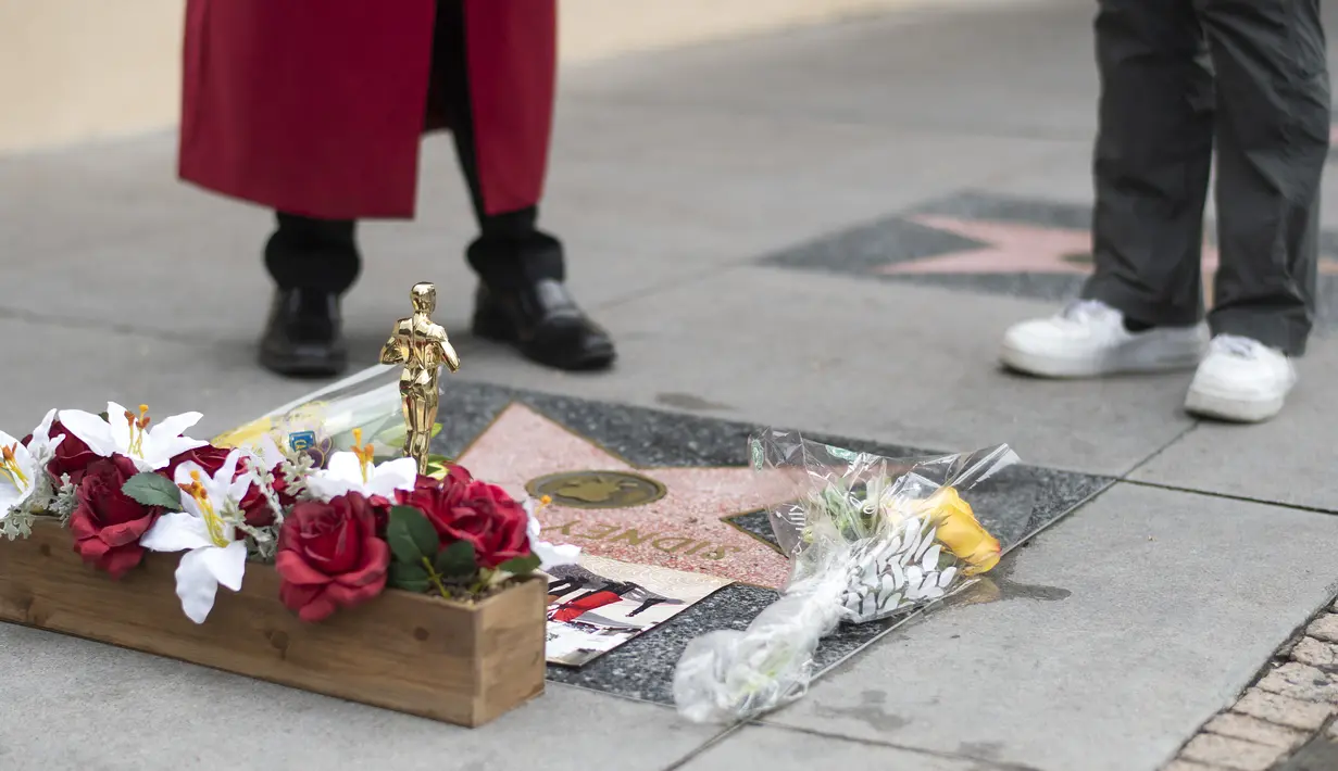 Orang-orang menaruh bunga pada bintang Sidney Poitier di Hollywood Walk of Fame di Hollywood, California, Jumat (7/1/2022). Poitier, bintang film kulit hitam pertama Hollywood dan pria kulit hitam pertama yang memenangkan aktor terbaik Oscar, meninggal pada usia 94 tahun. (VALERIE MACON/AFP)