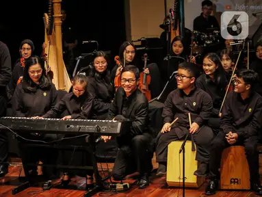 Konduktor Addie MS (tengah kanan) memimpin orkestra grup musik Light Ministry Orchestra (LMO) dan Light Ministry Ensemble (LME), yang mayoritas siswanya berkebutuhan khusus, saat konser A Night of Light di Jakarta, Minggu (19/11/2023). (Liputan6.com/Angga Yuniar)