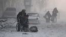 Seorang pria di kursi roda melarikan diri dengan sejumlah warga yang lain dari wilayah yang dikuasai pemberontak, Aleppo, Suriah (9/12). (REUTERS / Abdalrhman Ismail)