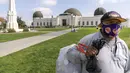 Jose Cartamo (64) dari El Salvador, memakai masker saat mengumpulkan barang daur ulang di Griffith Observatory di Los Angeles, Senin (17/5/2021). California mempertahankan aturan untuk mengenakan masker hingga negara bagian itu mencabut pembatasan COVID-19 pada 15 Juni. (AP Photo/Damian Dovarganes)