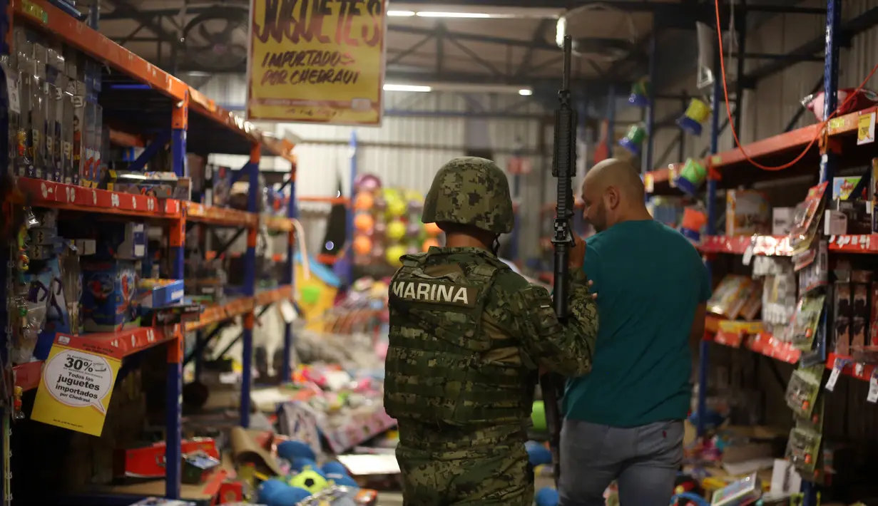 Polisi AL Meksiko mengamankan seorang pria yang melakukan penjarahan di sebuah toko di negara bagian Veracruz, Rabu (4/1). Penjarahan terjadi di sejumlah toko di Meksiko, seiring berlangsungnya unjuk rasa memprotes kenaikan harga BBM. (Ilse HUESCA/AFP)