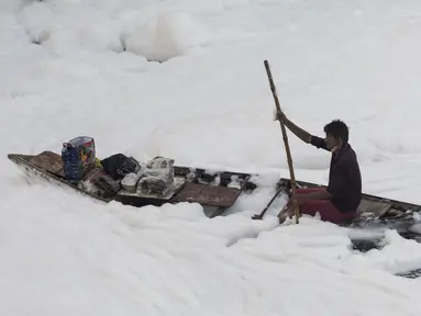 Seorang pria mendayung perahunya di tengah busa di sungai Yamuna yang tercemar di pinggiran New Delhi (23/7/2020). Sungai yang sangat dianggap suci oleh umat Hindu India ini masih tercemar, salah satunya akibat busa polusi memenuhinya. (AFP Photo/Xavier Galiana)