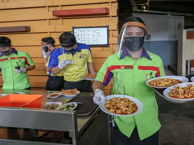 Pramusaji lengkap dengan Alat Pelindung Diri (APD) berupa face shield, sarung tangan dan masker membawa makanan untuk konsumen di Restoran Bandar Djakarta, Alam Sutera, Tangerang Selatan, Rabu (10/6/2020). Menuju new normal restoran tetap menerapkan protokol kesehatan. (Liputan6.com/Fery Pradolo)