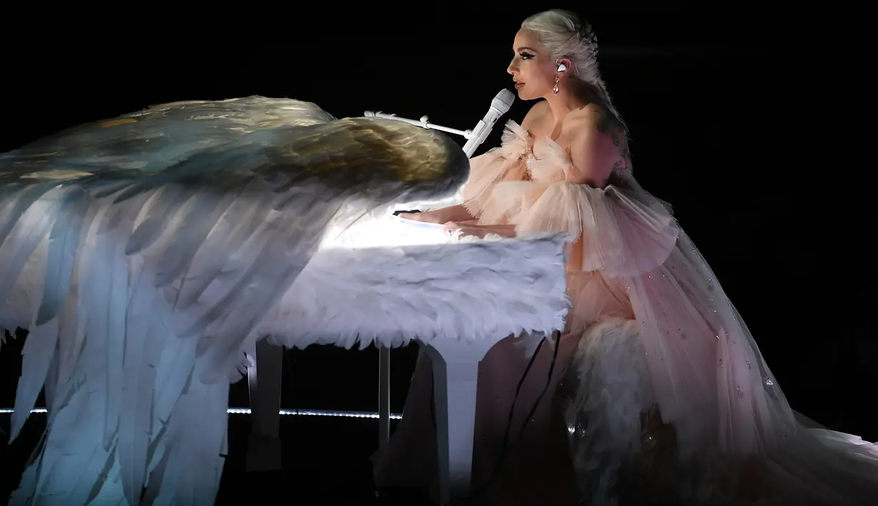 Penyanyi Lady Gaga tampil dengan piano putih berbalut sepasang sayap raksasa di panggung Grammy Awards 2018, New York,  Minggu (28/1). Bergaun baby pink yang memukau, Gaga membawakan lagu Joanne dan Million Reasons. (KEVIN WINTER/GETTY IMAGES/AFP)