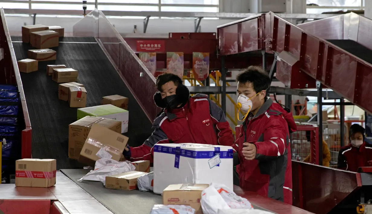 Kurir sibuk memilah paket di pusat distribusi di Beijing, China, Selasa (18/2/2020). Wabah virus corona atau COVID-19 membuat warga memilih untuk tinggal di rumah dan memanfaatkan jual beli secara online. (AP Photo/Ng Han Guan)