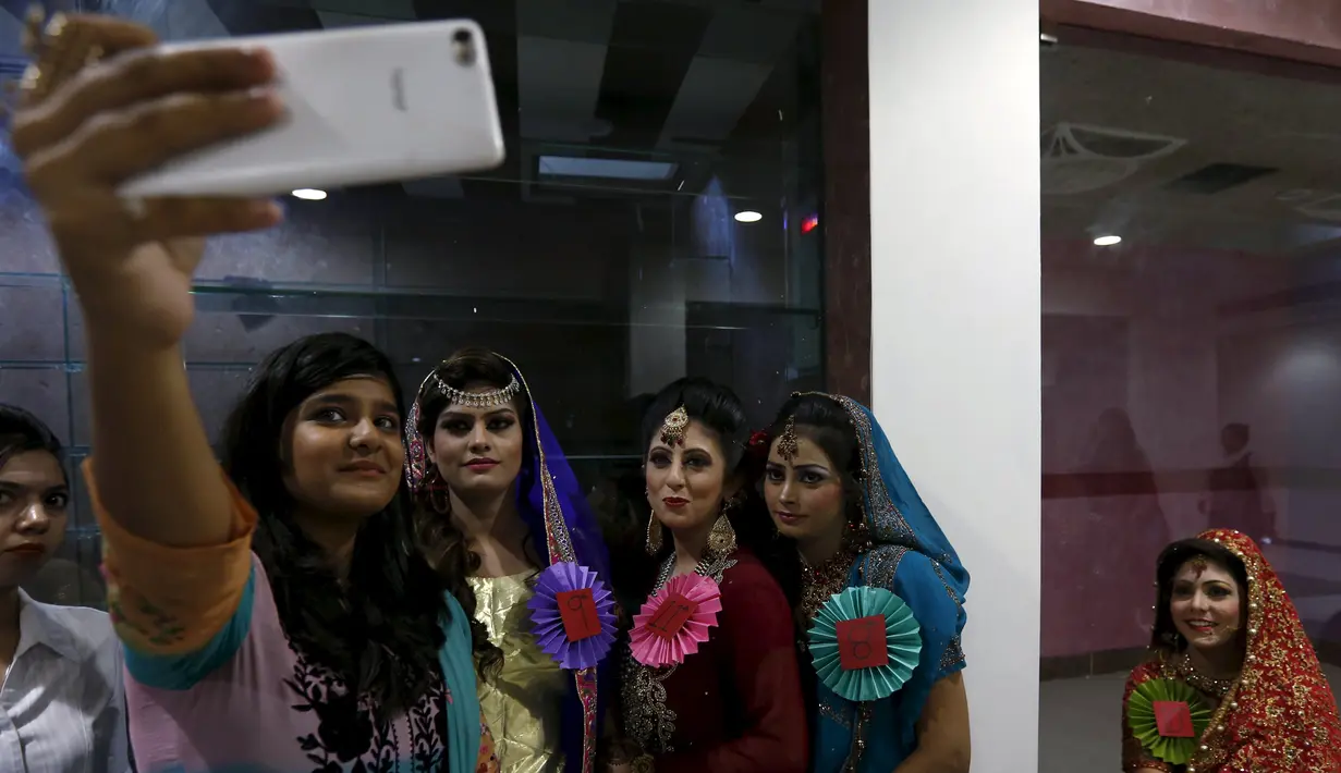 Sejumlah model berselfie di sela kegiatan lomba rias pengantin lokal di Karachi, Pakistan, 22 Maret 2016. Sejumlah wanita mengikuti lomba yang diadakan di sebuah pusat pembelajaan. (REUTERS / Akhtar Soomro)
