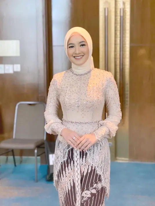Cut Syifa mengenakan kebaya modifikasi warna sampanye tanpa kancing dengan aksen payet seperti belt di momen pernikahan Lesti Kejora dan Rizky Billar. Kebaya ini memiliki detail asimetris di bagian bawah dan lengan bawah yang sedikit mengembang. Sementara untuk hijabnya, ia mengenakan scarf segi empat warna senada. [@cutsyifaa]
