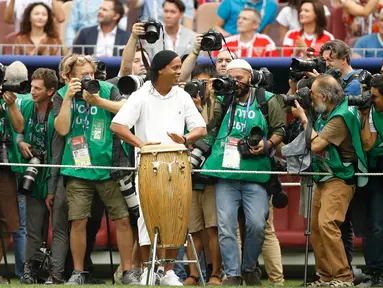 Legenda sepakbola Brasil, Ronaldinho dikelilingi oleh para fotografer saat menabuh jenis musik gendang, bongo pada seremonial final Piala Dunia 2018 di Stadion Luzhniki, Minggu (15/7). Kehadiran Ronaldinho membuat suporter antusias. (AP/Francisco Seco)