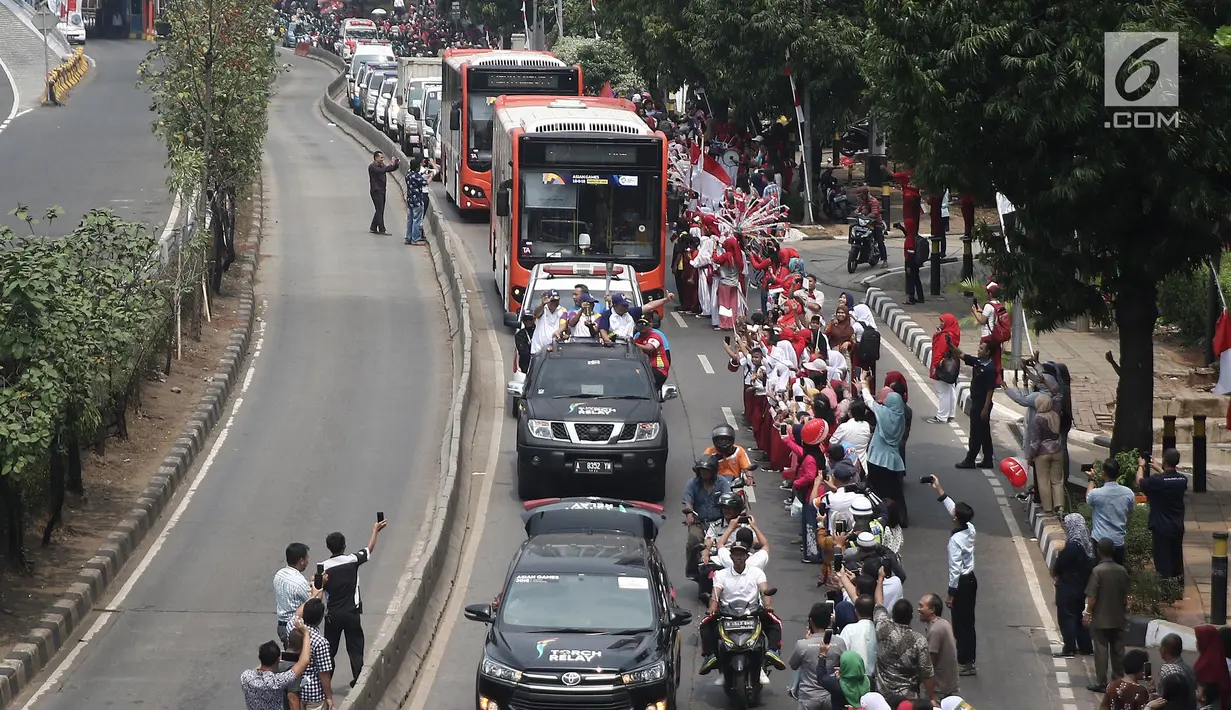 Masyarakat menyambut kedatangan Torch Relay Asian Games 2018 di kawasan Slipi, Jakarta, Kamis (16/08). Obor Asian Games 2018 tiba di wilayah Jakarta Barat  dan nantinya akan di teruskan berkeliling Jakarta Utara.(Liputan6.com/  Herman Zakharia)