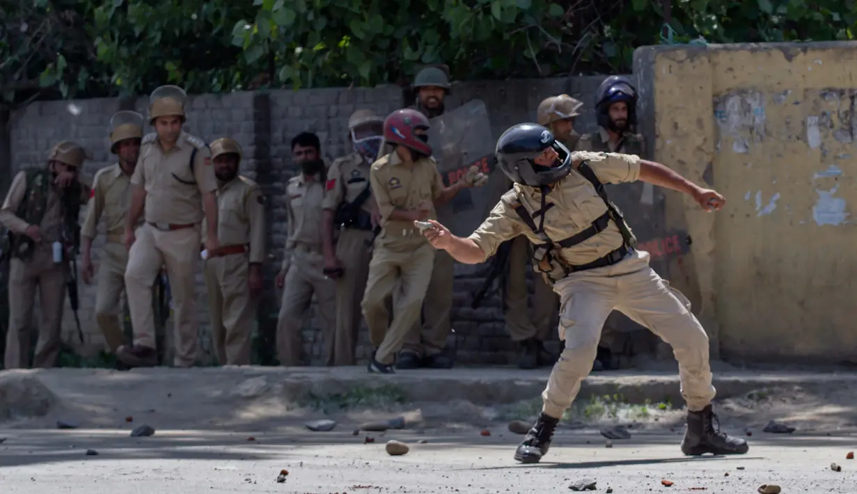 Polisi India melemparkan batu saat bentrok dengan mahasiswa Kashmir di Srinagar, Kashmir yang dikuasai India, (23/5). Bentrokan telah meningkat setelah tentara menggerebek sebuah perguruan tinggi di kota selatan Pulwama bulan lalu. (AP Photo/Dar Yasin)