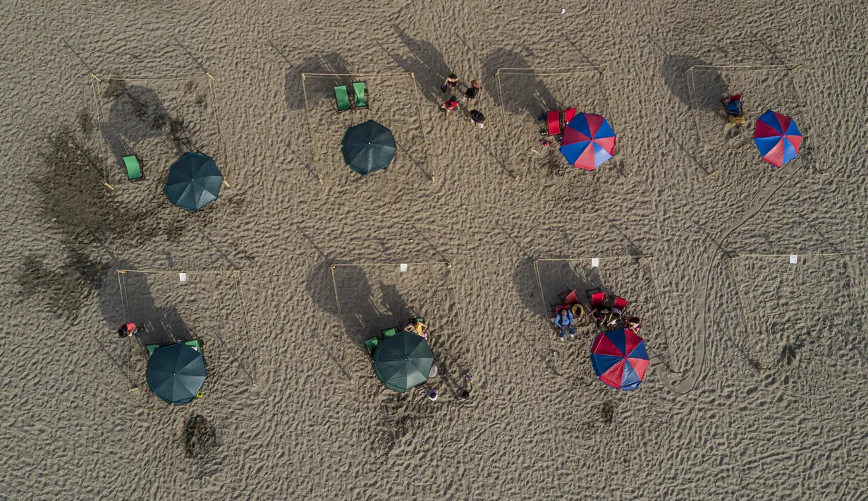Para pengunjung berjemur dalam pembatas untuk menghindari keramaian di tengah pandemi COVID-19 di Pantai Lima, Peru, Rabu (21/12/2021). Di pantai-pantai populer di Lima, pihak berwenang memutuskan membuat pembatas untuk mencegah kerumunan pengunjung. (Ernesto BENAVIDES/AFP)
