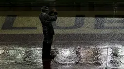 Seorang mengabadikan gambar dipinggir lapangan yang banjir akibat hujan lebat di stadion Monumental, Argentina, Jumat (13/11/2015). Karena cuaca buruk Pertandingan antara Argentina dan Brasil mengalami pengunduran. (REUTERS/Marcos Brindicci)