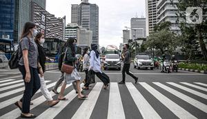 Orang-orang menyeberang jalan dengan latar belakang gedung perkantoran di kawasan Sudirman, Jakarta, Rabu (16/12/2020). Pemprov DKI Jakarta akan mengikuti arahan Wakil Ketua Komite Penanganan Covid-19 Luhut Binsar Pandjaitan terkait pengetatan work from home (WFH). (Liputan6.com/Faizal Fanani)