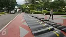 Seorang petugas melintas di dekat tameng polisi yang diletakan di sekitar pintu masuk Gedung MPR/DPR RI, Senayan, Jakarta, Jumat (31/3). Polda Metro Jaya memberikan pengamanan ketat di sekitar gedung DPR terkait aksi 31 Maret. (Liputan6.com/Johan Tallo)