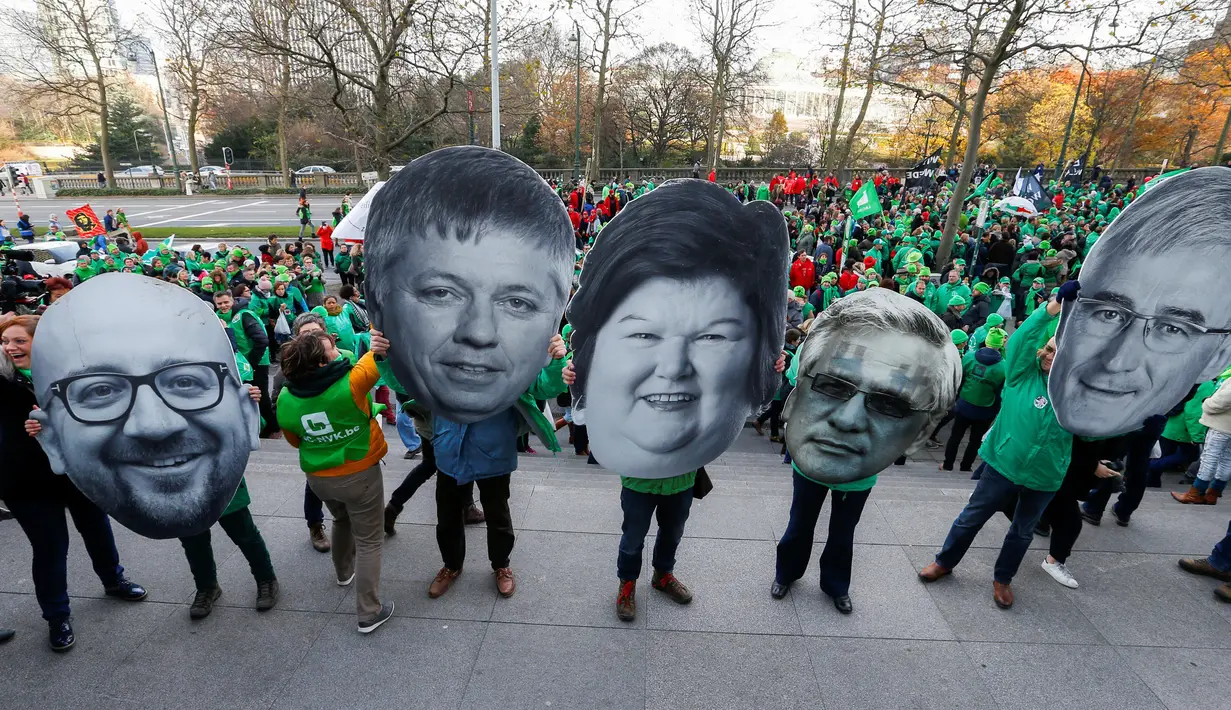 Demonstran mengenakan topeng yang menggambarkan Perdana Menteri Belgia Charles Michel (kiri), Sosial dan Menteri Kesehatan Maggie De Block (tengah) dan politisi lainnya di Belgia, Brussels, Kamis (24/11). (REUTERS / Yves Herman)