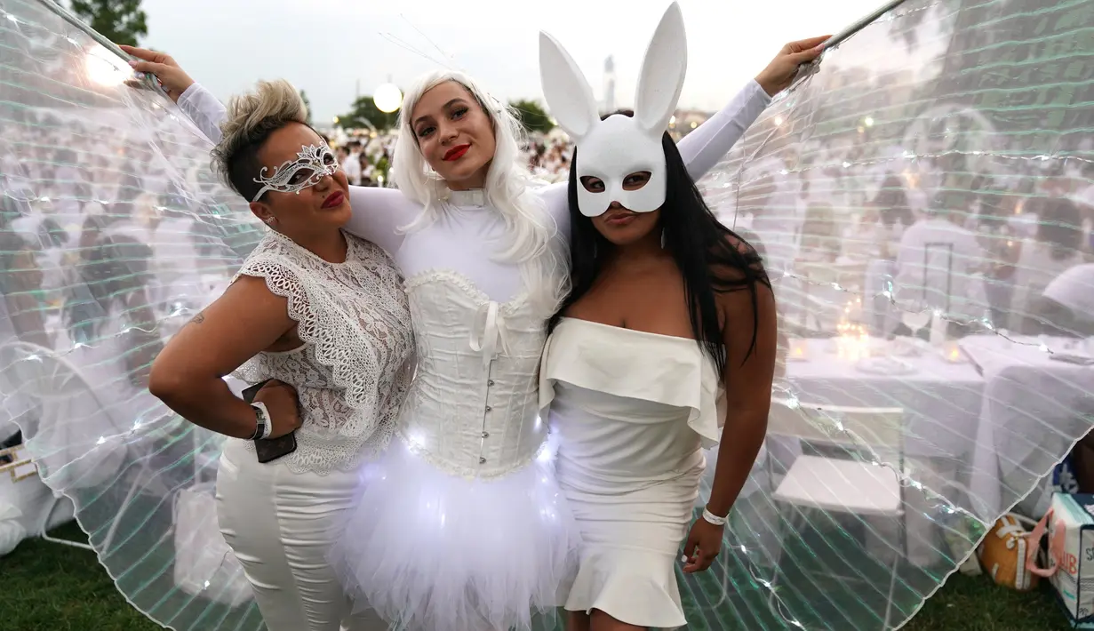 Peserta berpakaian serba putih berpose dalam Diner en blanc di Rockefeller Park, New York, Rabu (17/7/2019). New York City Diner en Blanc adalah sebuah pesta makan malam rahasia dengan pakaian bernuansa putih yang diadopsi dari budaya Prancis. (TIMOTHY A. CLARY / AFP)