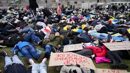 Orang-orang berbaring di tanah melambangkan mereka yang tewas dalam perang di Ukraina selama demonstrasi menentang invasi Rusia, dekat gedung parlemen Jerman, di Berlin, 6 April 2022. Pengunjuk rasa menuntut Berlin berhenti membeli minyak dan gas Rusia. (AP Photo/Markus Schreiber)