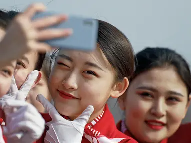 Sejumlah wanita berswafoto di sela penyambutan para peserta Kongres Rakyat Nasional di Beijing, China, Senin (4/3). Para wanita berparas cantik tersebut bertugas menyambut para tamu yang menghadiri kongres. (AP Photo/Andy Wong)