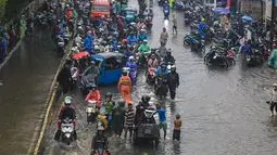 Meski kondisi jalan tergenang, sejumlah pengendara tetap melintas dengan berhati-hati untuk melanjutkan aktivitas. Tampak dalam foto, penumpukan pengendara terjebak banjir yang menggenangi Jalan Jembatan Tiga Raya, Jakarta Utara, Senin (12/1/2026). (merdeka.com/Arie Basuki)