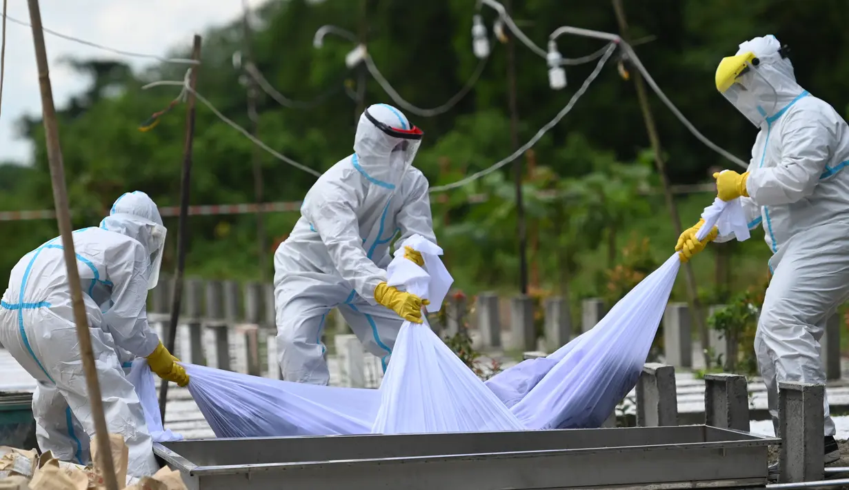 Relawan yang mengenakan pakaian pelindung diri (APD) menurunkan ke dalam kuburan jenazah seseorang yang diduga meninggal akibat virus Corona Covid-19 di sebuah pemakaman, di Yangon (26/10/2020). (AFP/Ye Aung Thu)