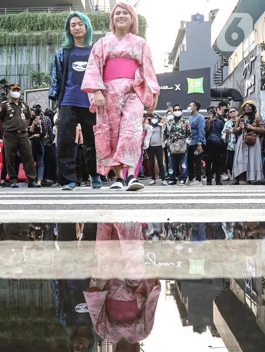 Evelyn Nada Anjani dan DJ nomor satu di Jepang, DJ Shacho berpose menampilkan busananya di atas zebra cross di kawasan Dukuh Atas, Jakarta, Selasa (26/7/2022). Evelyn dan DJ Shacho ikut meramaikan fenomena Citayam Fashion Week dengan tampil mengenakan busana khas negeri Sakura, Jepang. (Liputan6.com/Faizal Fanani)