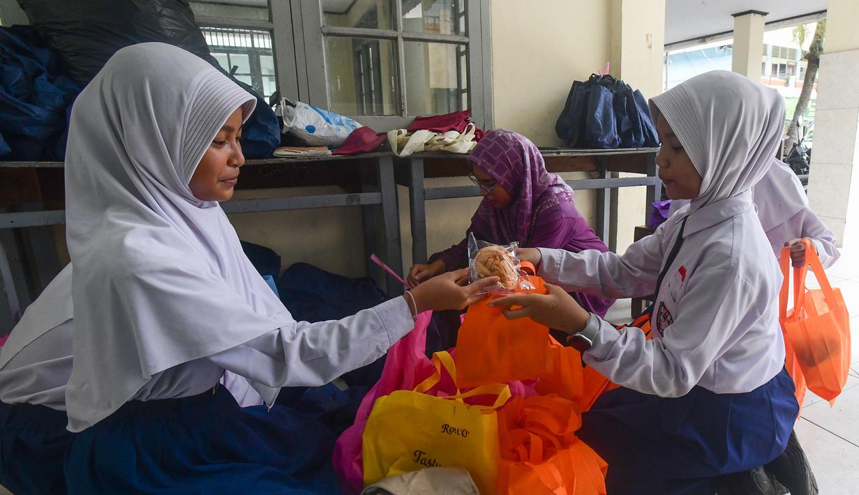 Program berjalan dengan sejumlah penyesuaian khusus. Tampak dalam foto, siswa memilah makanan program Makan Bergizi Gratis (MBG) Ramadan yang akan didistribusikan kepada temen-temannya di SDI Al Hidayah, Cinere, Depok, Selasa (24/2/2026). (merdeka.com/Arie Basuki)