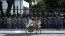 Seorang pedagang melintas di dekat polisi yang berjaga di lokasi pertemuan ASEAN di Manila Bay, Filipina, Rabu (26/4). Sekitar 40 ribu pasukan keamanan dikerahkan untuk menjaga acara tersebut. (AFP PHOTO / Noel CELIS)