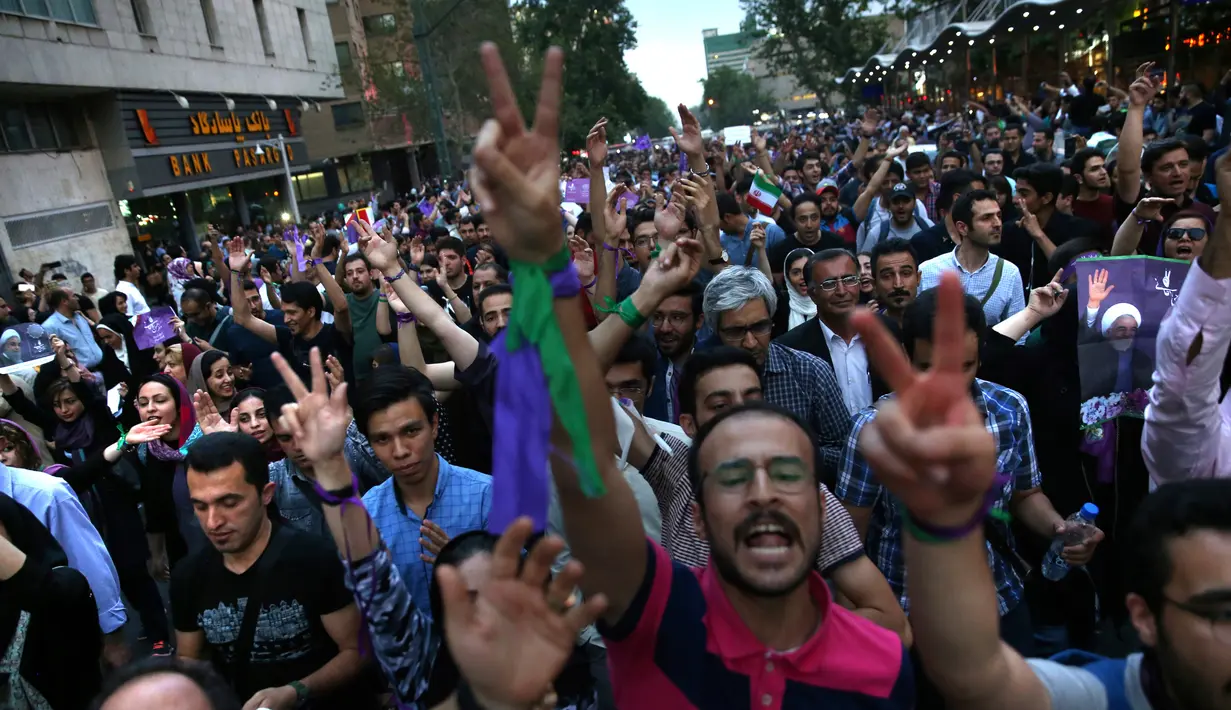 Pendukung Presiden Iran Hassan Rouhani merayakan kemenangannya usai pengumuman di Teheran, Iran (20/5). Rouhani meraih dukungan 23,5 juta pemilih atau 57 persen suara, dengan menyisihkan saingan utamanya Ebrahim Raisi. (AP Photo/Ebrahim Noroozi)