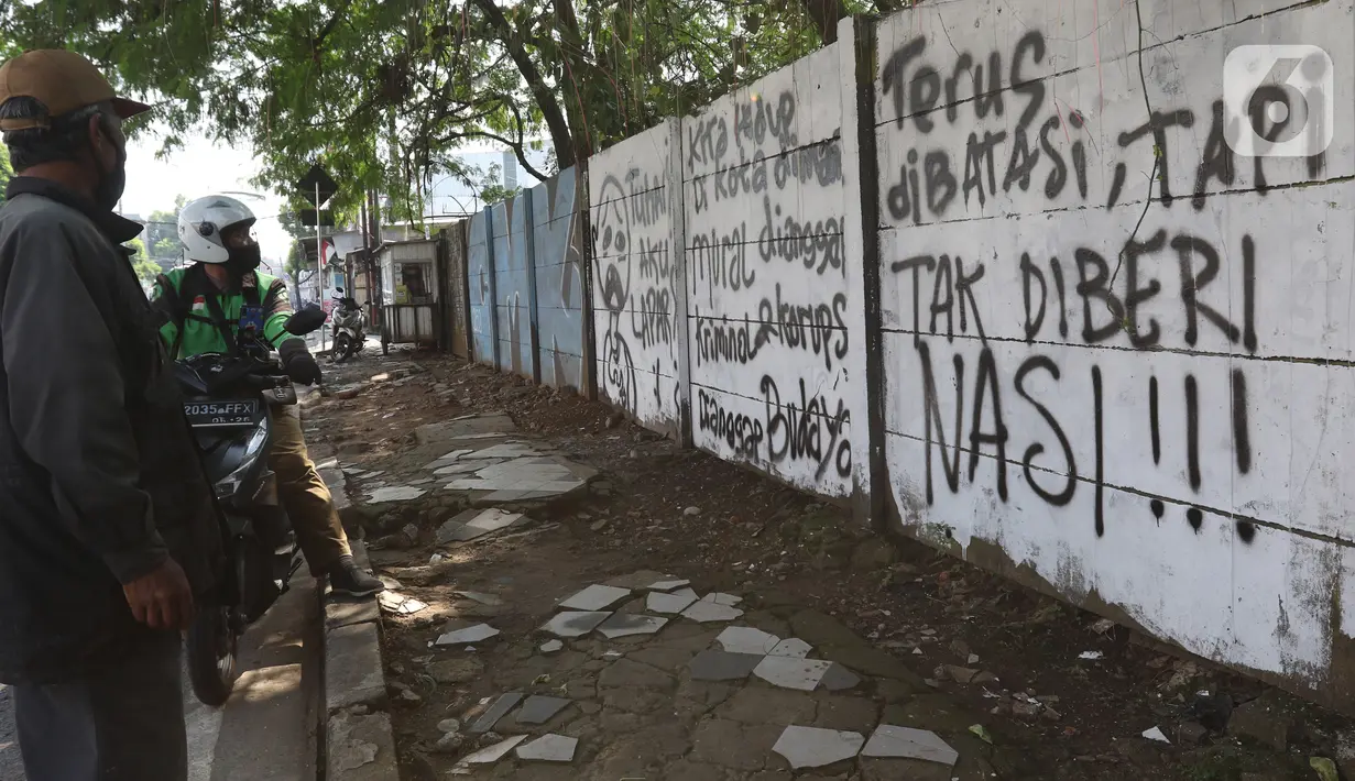 Pengguna jalan melihat mural di kawasan Citayam, Depok, Jawa Barat, Rabu (25/8/2021). Mural tersebut merupakan wujud ekspresi dari sejumlah seniman serta sebagai media penyampaian kritik sosial kepada pemerintah di tengah pandemi COVID-19. (Liputan6.com/Herman Zakharia)