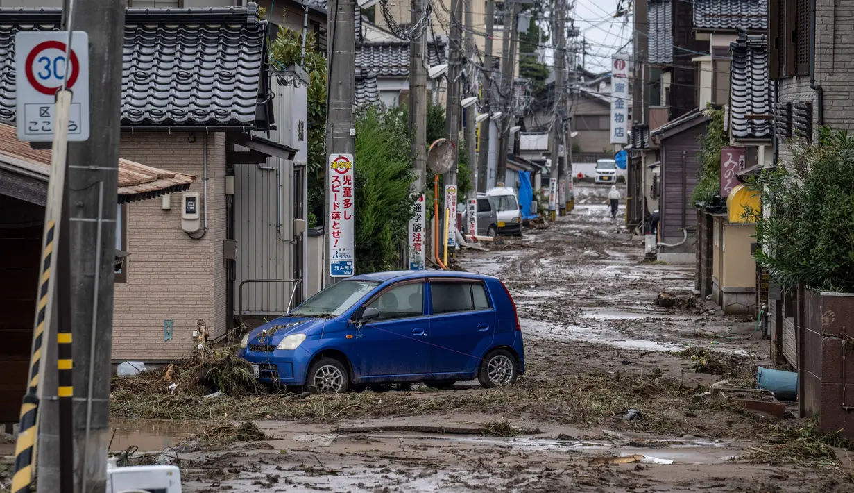 Sebuah mobil yang terdampar terlihat di jalan yang tertutup lumpur setelah hujan lebat di kota Wajima, prefektur Ishikawa, Jepang, pada tanggal 22 September 2024. (Yuichi YAMAZAKI/AFP)