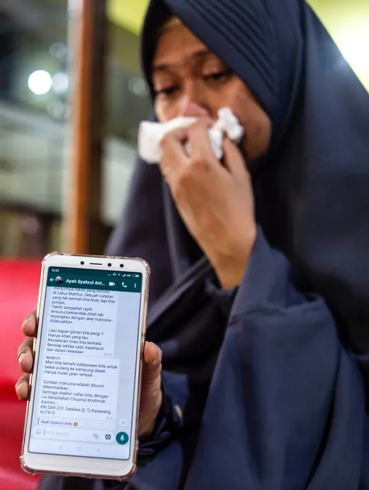 Lyan Kurniawati, istri dari penyelam Syachrul Anto yang meninggal dunia saat melakukan evakuasi jatuhnya pesawat Lion Air PK-LQP, menunjukkan pesan terakhir sang suami setelah prosesi pemakaman di Surabaya, Jawa Timur, Sabtu (3/11). (JUNI KRISWANTO/AFP)