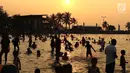 Pengunjung berenang jelang matahari tenggelam di kawasan wisata Pantai Karnaval Ancol, Jakarta, Sabtu (16/6). H+1 libur Lebaran, jumlah pengunjung di Ancol mencapai 88.143 orang. (Liputan6.com/Immanuel Antonius)