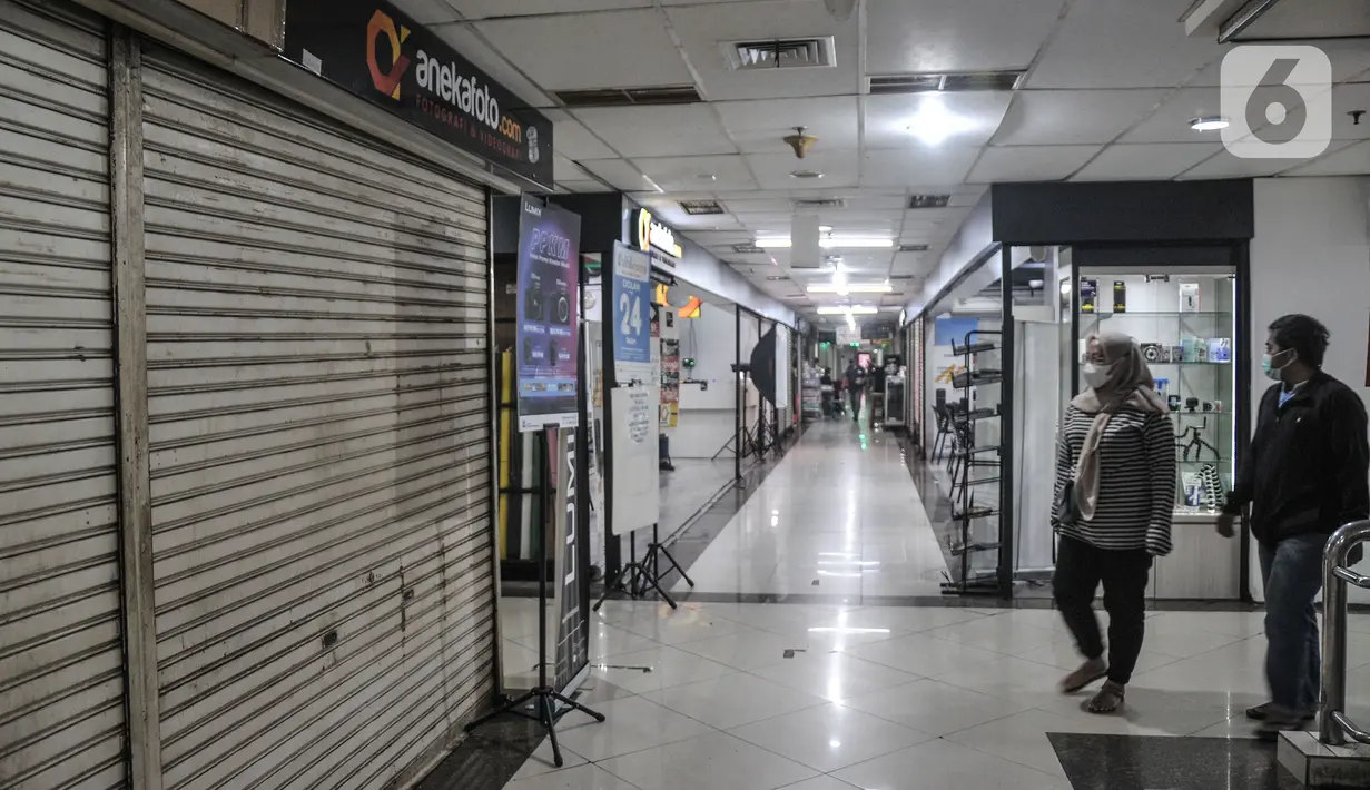 Pengunjung melintasi salah satu toko kamera yang tutup di Metro Atom Plaza, Pasar Baru, Jakarta, Senin (15/11/2021). Akibat menurunnya omzet selama pandemi Covid-19, sejumlah toko kamera di Pasar Baru terpaksa gulung tikar. (merdeka.com/Iqbal S Nugroho)
