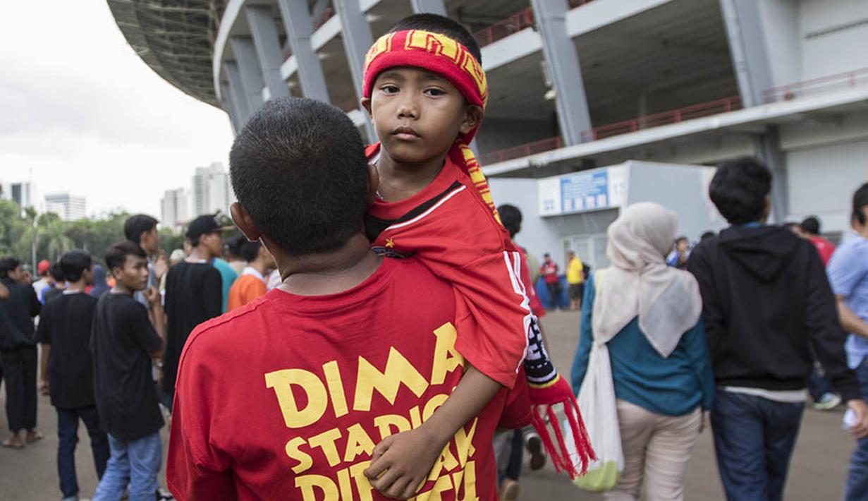 Seorang bapak menggendong anaknya pendukung tim 'Kabau Sirah' Semen Padang jelang final Piala Jenderal Sudirman antara Semen Padang melawan Mitra Kukar di Stadion Utama Gelora Bung Karno, Jakarta, Minggu (24/1/2016). (Bola.com/Vitalis Yogi Trisna)