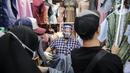 Pedagang menggunakan alat pelindung wajah (Face Shield) saat melayani pembeli di Kawasan Tanah Abang, Jakarta, Senin (18/5/2020). Penggunaan alat pelindung wajah itu sebagai upaya untuk melindungi diri saat berhubungan dengan pembeli dalam pecegahan penyebaran COVID-19. (Liputan6.com/Faizal Fanani)
