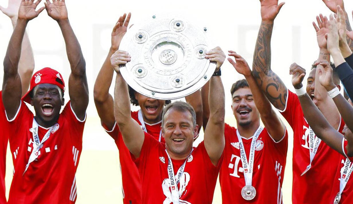 Pelatih Bayern Munchen, Hansi Flick, mengangkat trofi juara Bundesliga usai melawan Wolfsburg di Volkswagen Arena, Sabtu (27/6/2020). Kemenangan itu membuat Bayern kokoh di puncak klasemen sekaligus mengunci gelar juara Bundesliga. (AP/Kai Pfaffenbach)