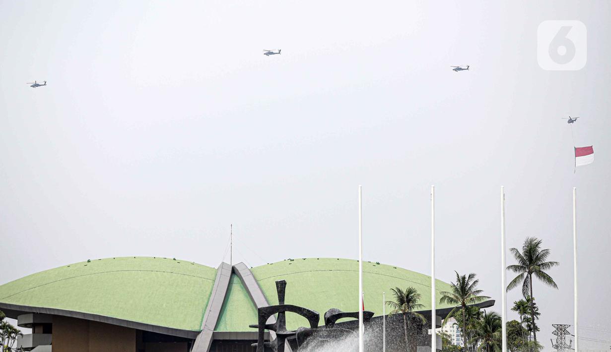 Helikopter TNI AU mengibarkan bendera Merah Putih raksasa di kawasan Gedung DPR RI, Jakarta, Selasa (5/10/2021). Bendera raksasa ini dikibarkan dari timur ke barat langit Jakarta dalam rangka memperingati Hut ke-76 TNI. (Liputan6.com/Faizal Fanani)