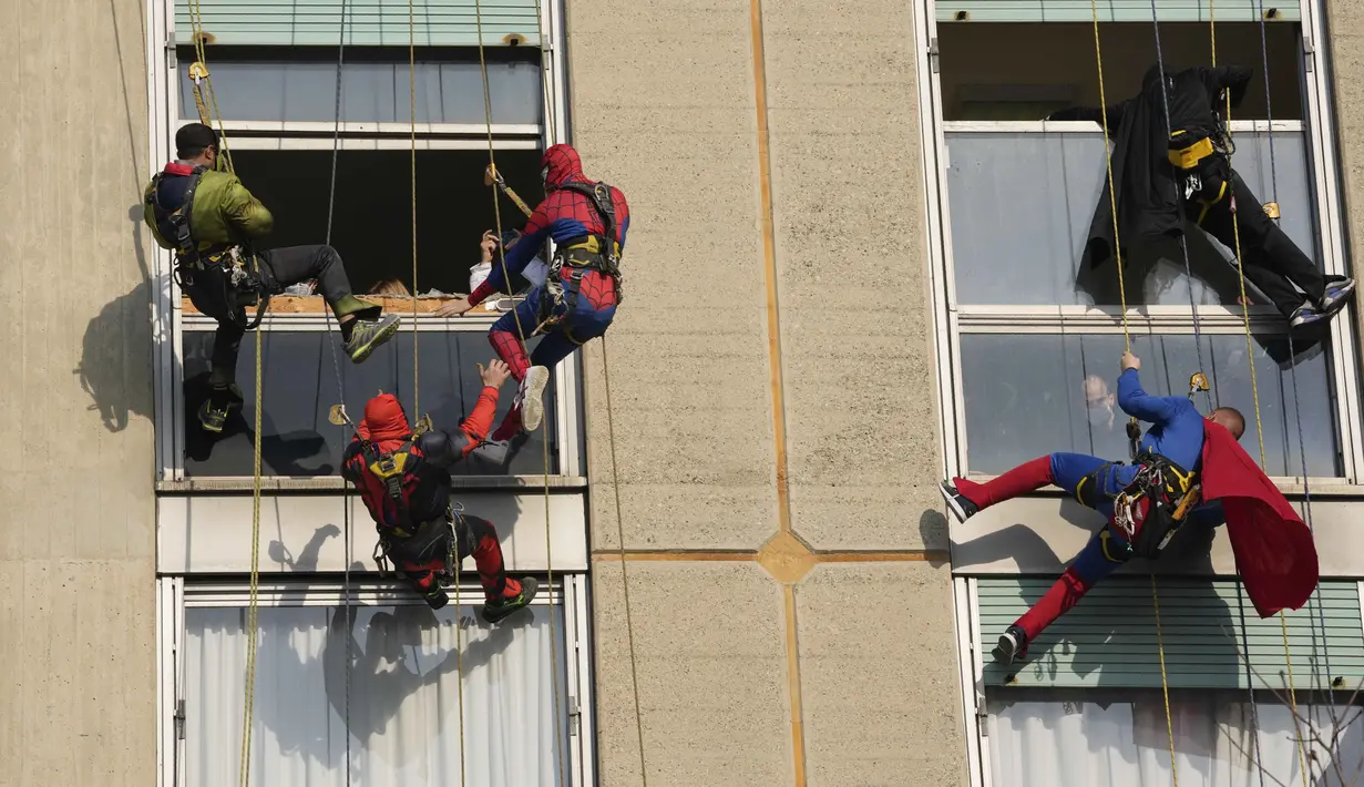 Sejumlah orang berpakaian superhero turun dari atap untuk memberi kejutan di jendela kamar pasien anak di bangsal Pediatri rumah sakit San Paolo di Milan, Italia, Rabu (15/12/2021). Aksi Spiderman dkk itu untuk menghibur anak-anak yang dirawat di rumah sakit tersebut. (AP Photo/Luca Bruno)