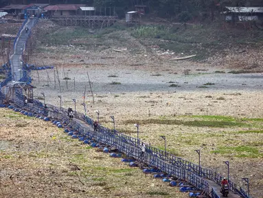Orang-orang melintas di atas jembatan terapung sepanjang 300 meter yang melintasi Sungai Citarum yang mengering di Cihampelas, Jawa Barat pada 4 Oktober 2023. (Timur MATAHARI/AFP)
