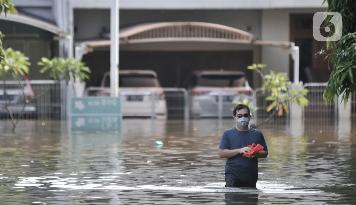 Warga melintasi banjir rob yang merendam Kompleks Perumahan Pantai Mutiara, Pluit, Jakarta, Minggu (7/6/2020). (merdeka.com/Iqbal S. Nugroho)