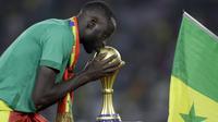 Gelandang Senegal Cheikhou Kouyate mencium trofi setelah memenangkan pertandingan final Piala Afrika 2022 atas Mesir di Paul Biya Stadium, Kamerun, Senin (7/2/2022) dini hari WIB. Sadio Mane membawa Senegal mengalahkan Mesir lewat adu penalti dengan skor 4-2. (AP Photo/Sunday Alamba)