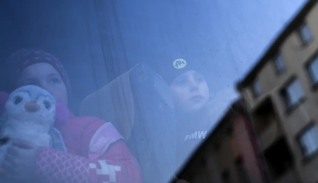 Anak-anak yang melarikan diri dari perang di Ukraina menunggu di bus setelah tiba di stasiun kereta api Przemysl di Przemysl, Polandia tenggara, Kamis (17/3/2022). Polandia telah menerima sekitar 1,95 juta pengungsi yang melarikan diri dari perang dan agresi Rusia di Ukraina. (AP Photo/Petros Gianna
