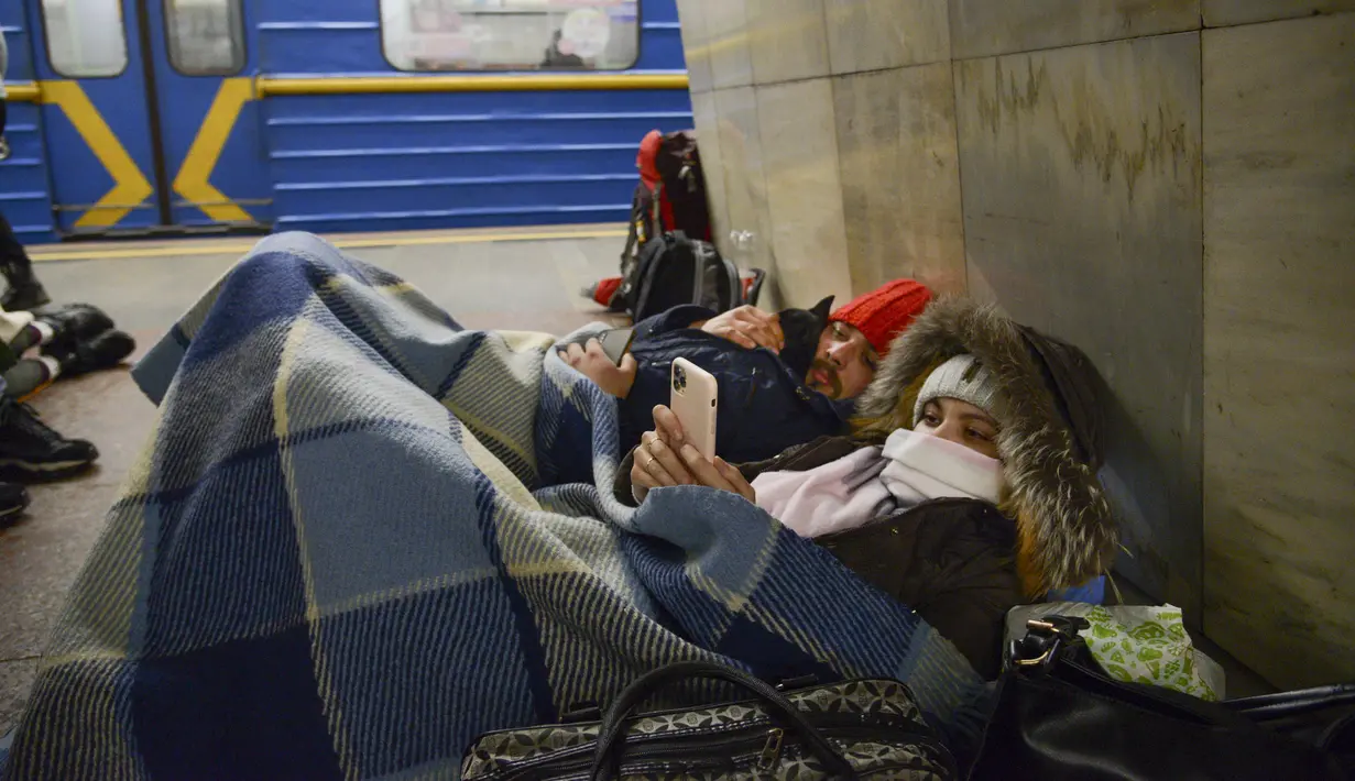Orang-orang berbaring di kereta bawah tanah Kiev, menggunakannya sebagai tempat perlindungan bom di ibu kota Ukraina, Kamis, 24 Februari 2022. Warga di Kiev tampak berlindung di stasiun bawah tanah kota dan tempat-tempat aman lainnya untuk menghindari invasi Rusia. (AP Photo/Emilio Morenatti)
