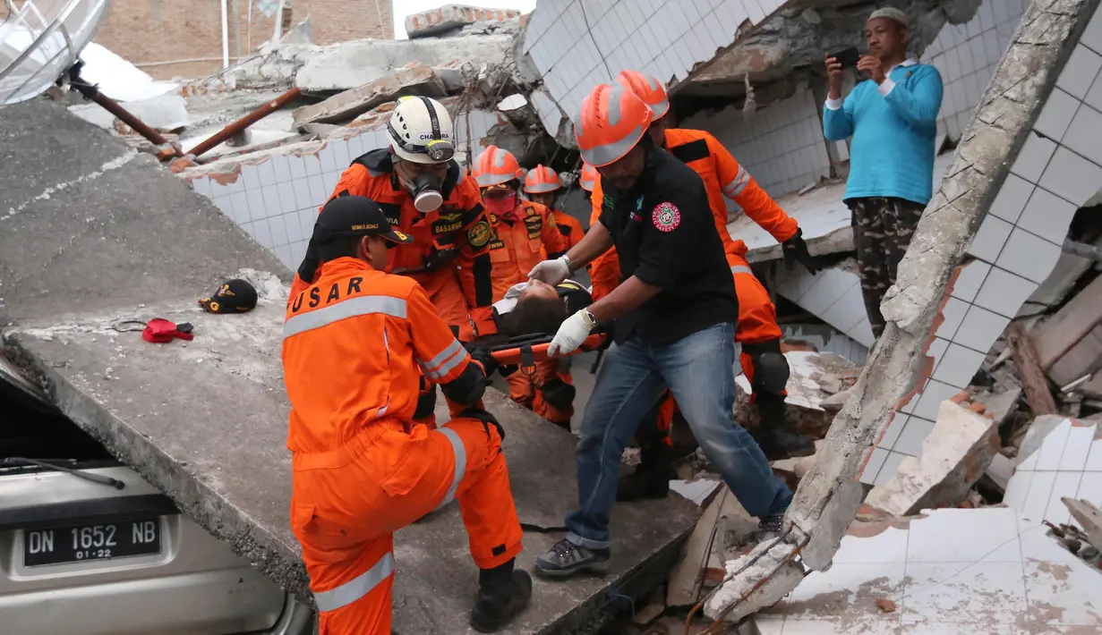 Tim penyelamat membawa korban selamat dari sebuah bangunan restoran yang rusak akibat gempa dan tsunami yang menghantam Palu, Sulawesi Tengah, Minggu (30/9). (AP Photo/Tatan Syuflana, File)