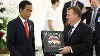 Perdana Menteri Denmark Lars Lokke Rasmussen memberikan Presiden Joko Widodo (Jokowi) cendera mata piringan hitam band Metallica usai pernyataan bersama dalam kunjungan kerja PM Denmark di Istana Bogor, Jawa Barat, Selasa (28/11). (AP/Dita Alangkara)