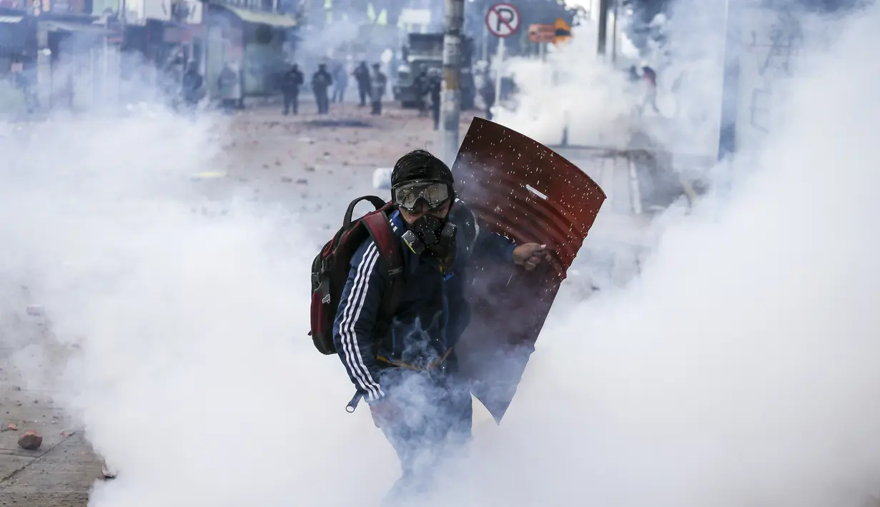 Seorang pengunjuk rasa anti-pemerintah berlari melewati awan gas air mata selama bentrokan dengan polisi di Madrid, di pinggiran Bogota, Kolombia (28/5/2021). (AP Photo/Ivan Valencia)